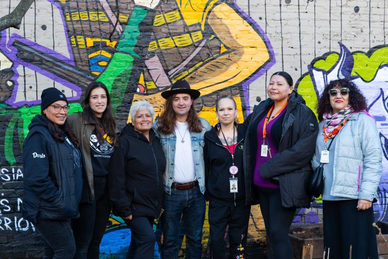 The Indigenous Health Outreach team standing in front of a mural