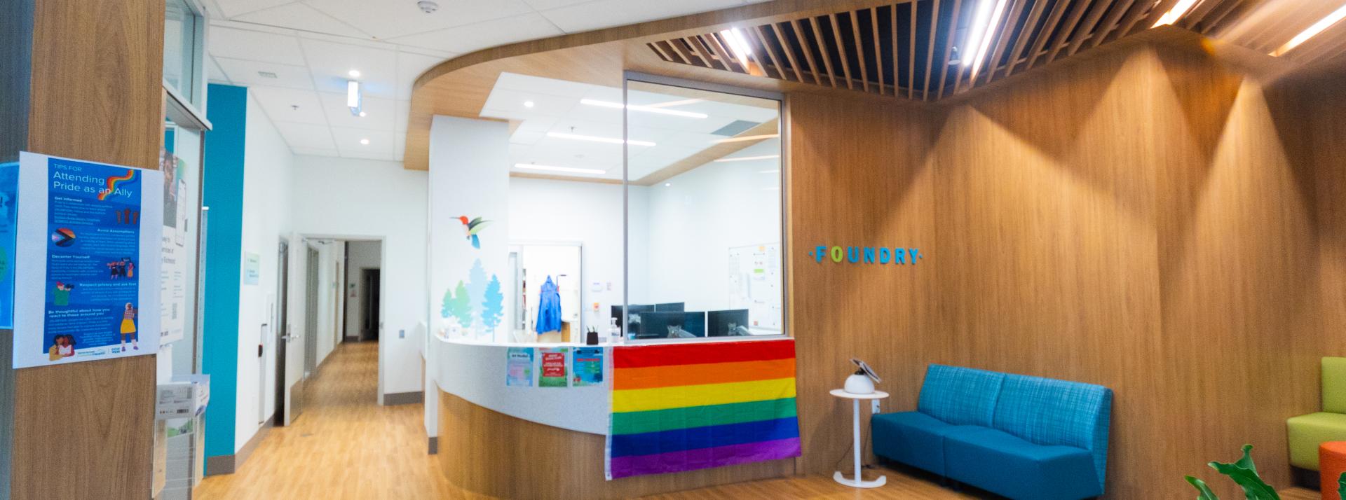 Reception area at Foundry Richmond. There is a large rainbow Pride flag hung at the reception desk.