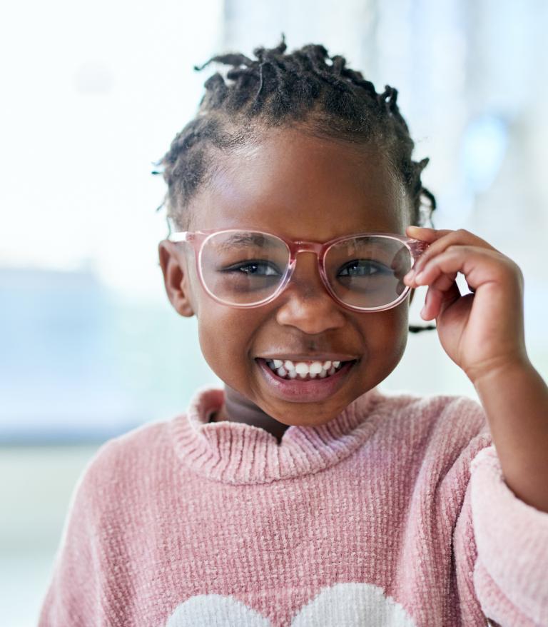 Young child smiling wearing glasses in an optometrist's office