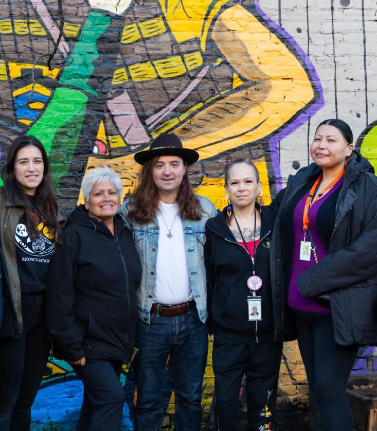 The Indigenous Health Outreach team standing in front of a mural