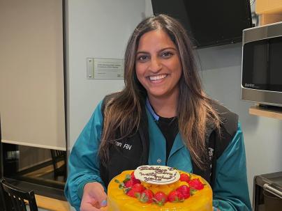 Simran Bir, Specialty Nurse/RN-ICU, standing with a cake in hand.