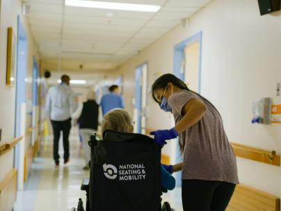 A staff member guides a patient in a wheelchair down the hallway of the interim home at George Pearson Centre