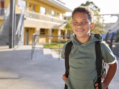 Child smiling outside of a school