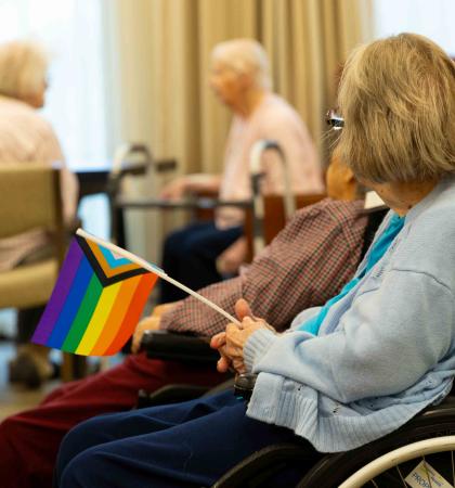 Resident holding an inclusive Pride flag to virtually celebrate the 2023 Vancouver Pride Parade and Festival.