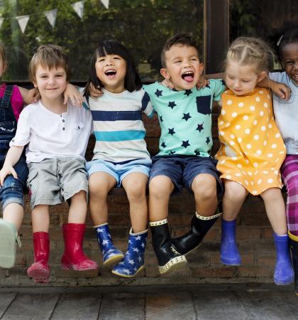 A group photo of six children laughing outside.